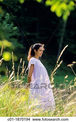 Picture - Pregnant woman standing in meadow. Fotosearch
