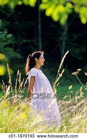 Pregnant woman standing in meadow View Large Photo Image Stock Image - Pregnant woman standing in meadow. Fotosearch