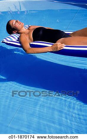 Pregnant woman sunbathing on mattress in swimming pool View Large Photo Image Picture - Pregnant woman sunbathing on mattress in swimming pool. Fotosearch