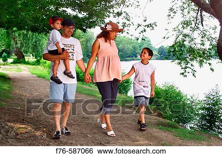 Stock Photograph - Pregnant woman walking alongside river with her husband and two young boys.. Fotosearch