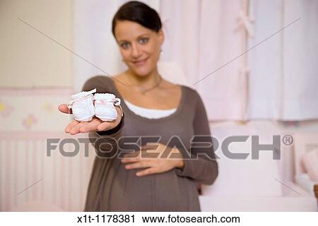 Stock Image - Pregnant woman with baby booties.. Fotosearch