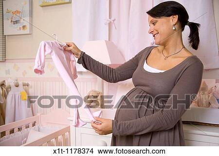 Pregnant woman with baby clothes. View Large Photo Image Picture - Pregnant woman with baby clothes.. Fotosearch