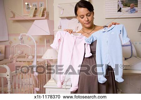 Stock Image - Pregnant woman with baby clothes.. Fotosearch