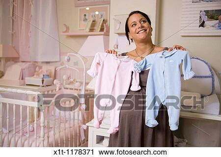 Stock Image - Pregnant woman with baby clothes.. Fotosearch