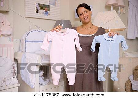 Stock Photo - Pregnant woman with baby clothes.. Fotosearch