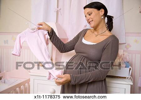 Stock Photography - Pregnant woman with baby clothes.. Fotosearch