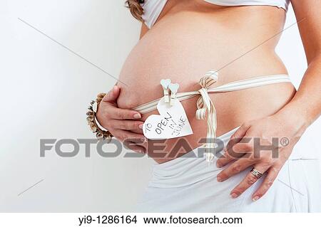 Picture - Pregnant woman with gift ribbon on belly. Fotosearch
