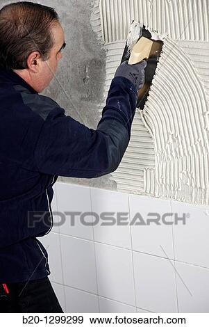 Preparing wall with glue mortar before tiling using a serrated plastering trowel, new homes under construction, construction site View Large Photo Image Stock Photo - Preparing wall with glue mortar before tiling using a serrated plastering trowel, new homes under construction, construction site. Fotosearch