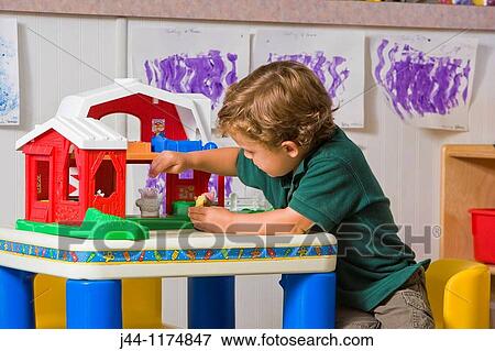 Stock Photo - Preschooler boy playing in the classroom with toy barn. Fotosearch