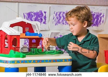 Preschooler boy playing in the classroom with toy barn View Large Photo Image Stock Photograph - Preschooler boy playing in the classroom with toy barn. Fotosearch