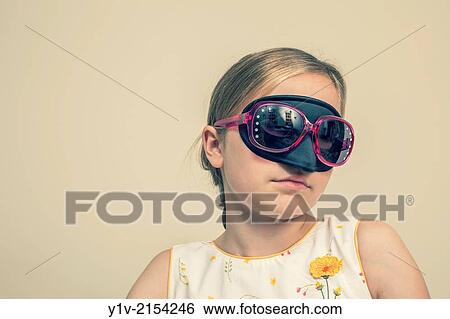 Stock Photograph - Preteen blond girl wearing a mask and sunglasses.. Fotosearch
