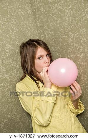 Stock Photo - Preteen girl blowing up a balloon. Fotosearch