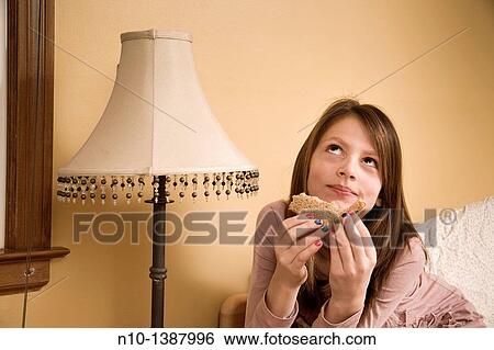 Preteen girl eating a sandwich in her bedroom View Large Photo Image Stock Photograph - Preteen girl eating a sandwich in her bedroom. Fotosearch