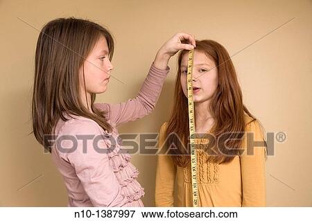 Preteen girl measuring her friend with a tape measure View Large Photo Image Stock Photo - Preteen girl measuring her friend with a tape measure. Fotosearch