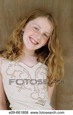 Preteen girl with long gold-brown hair and freckles, smiling at camera, head tilted to side, waist up, against brown wood background View Large Photo Image Stock Photo - Preteen girl with long gold-brown hair and freckles, smiling at camera, head tilted to side, waist up, against brown wood background. Fotosearch