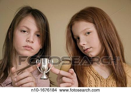 Picture - Preteen girls holding a miniature trophy cup. Fotosearch