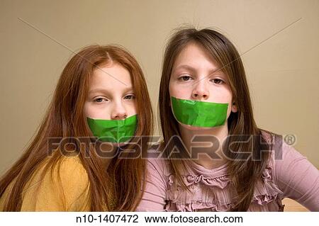 Stock Image - Preteen girls with green tape on their mouths. Fotosearch