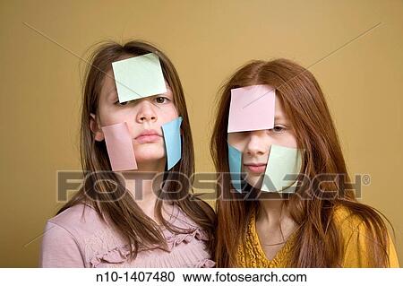 Stock Image - Preteen girls with post-it notes on their faces. Fotosearch