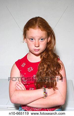 Stock Photo - Preteen redhead girl standing in front of a small food freezer, thinking.. Fotosearch
