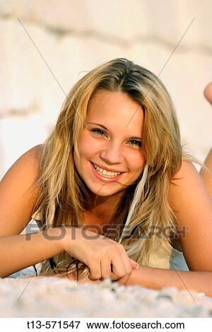 Stock Photo - Pretty blonde girl happy lying on the beach. Fotosearch