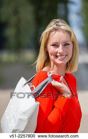 Stock Image - Pretty blonde woman happy with her shopping bag. Fotosearch