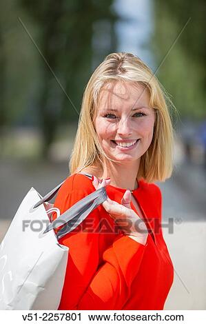 Stock Image - Pretty blonde woman happy with her shopping bag. Fotosearch