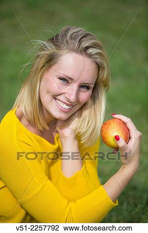 Pretty blonde woman with apple in park View Large Photo Image Stock Image - Pretty blonde woman with apple in park. Fotosearch