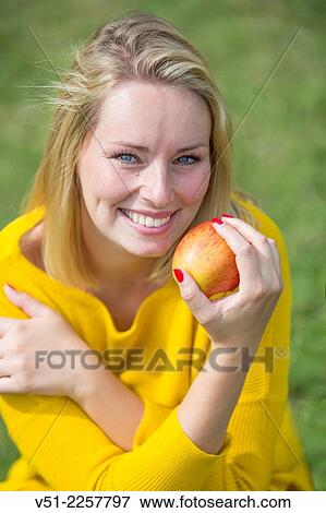 Pretty blonde woman with apple in park View Large Photo Image Stock Photo - Pretty blonde woman with apple in park. Fotosearch