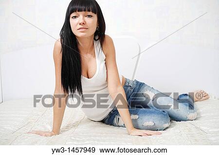 pretty brunette girl in jeans sitting on the bed View Large Photo Image Stock Photo - pretty brunette girl in jeans sitting on the bed. Fotosearch