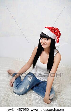Stock Image - pretty brunette girl in Santa hat indoors. Fotosearch