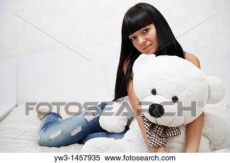 pretty brunette girl indoors embracing with big teddy bear on sofa View Large Photo Image Stock Photography - pretty brunette girl indoors embracing with big teddy bear on sofa. Fotosearch