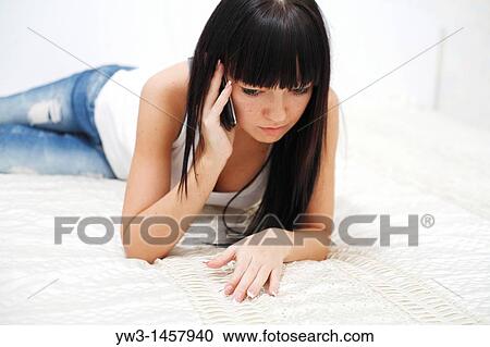 pretty brunette girl indoors lying on bed speaking on cell phone View Large Photo Image Stock Image - pretty brunette girl indoors lying on bed speaking on cell phone. Fotosearch