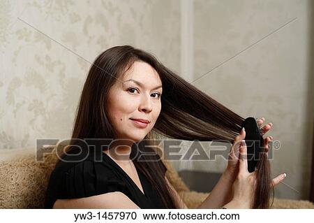 Stock Image - pretty brunette girl indoors on modern sofa. Fotosearch