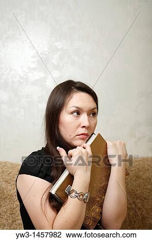 Stock Image - pretty brunette girl indoors on modern sofa. Fotosearch