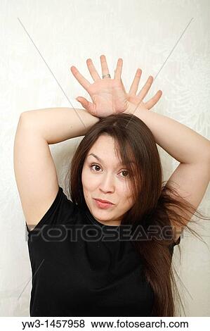 Stock Photo - pretty brunette girl indoors on modern sofa. Fotosearch