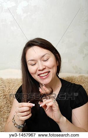 Stock Photo - pretty brunette girl indoors on modern sofa. Fotosearch