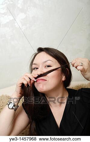 Stock Photo - pretty brunette girl indoors on modern sofa. Fotosearch
