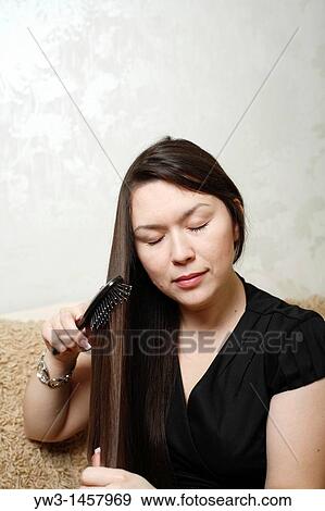 Stock Photo - pretty brunette girl indoors on modern sofa. Fotosearch