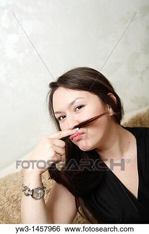 Stock Photograph - pretty brunette girl indoors on modern sofa. Fotosearch