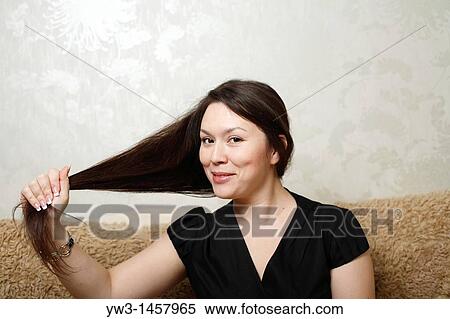Stock Photography - pretty brunette girl indoors on modern sofa. Fotosearch