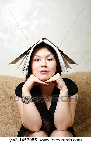 Stock Photography - pretty brunette girl indoors on modern sofa. Fotosearch