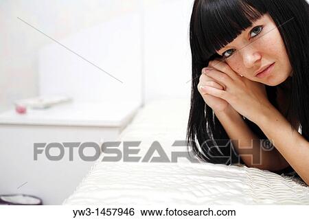 Stock Photograph - pretty brunette girl indoors on the bed smiling. Fotosearch