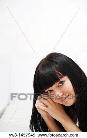 Stock Photography - pretty brunette girl indoors on the bed smiling. Fotosearch