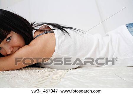 Stock Photo - pretty brunette girl indoors on the sofa. Fotosearch