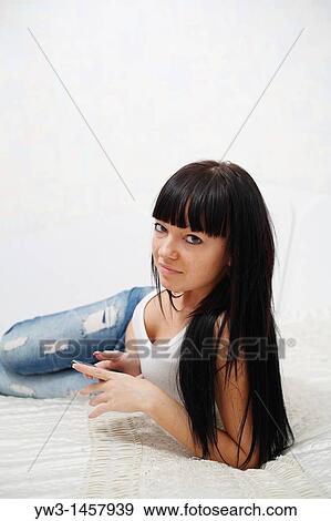 Stock Photo - pretty brunette girl indoors with cell phone. Fotosearch