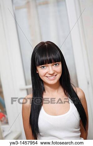 Picture - pretty brunette girl indoors with window on background. Fotosearch