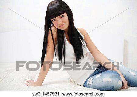 Stock Image - pretty brunette girl on the bed indoors. Fotosearch