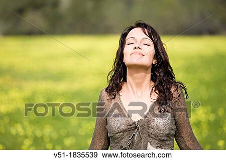 Stock Photo - Pretty brunette woman breathing fresh air in countryside. Fotosearch