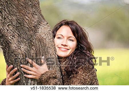 Stock Photo - Pretty brunette woman embracing tree. Fotosearch