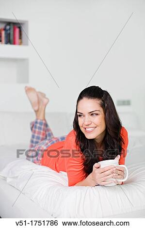 Stock Photograph - Pretty brunette woman enjoying breakfast in bed. Fotosearch